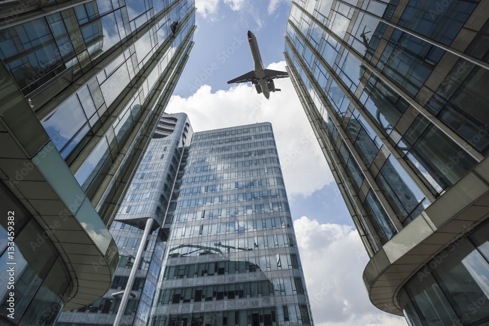 一架客机在现代玻璃建筑上空飞行