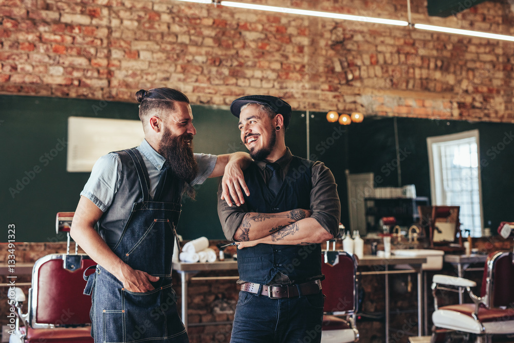 Happy barber with client standing at barbershop