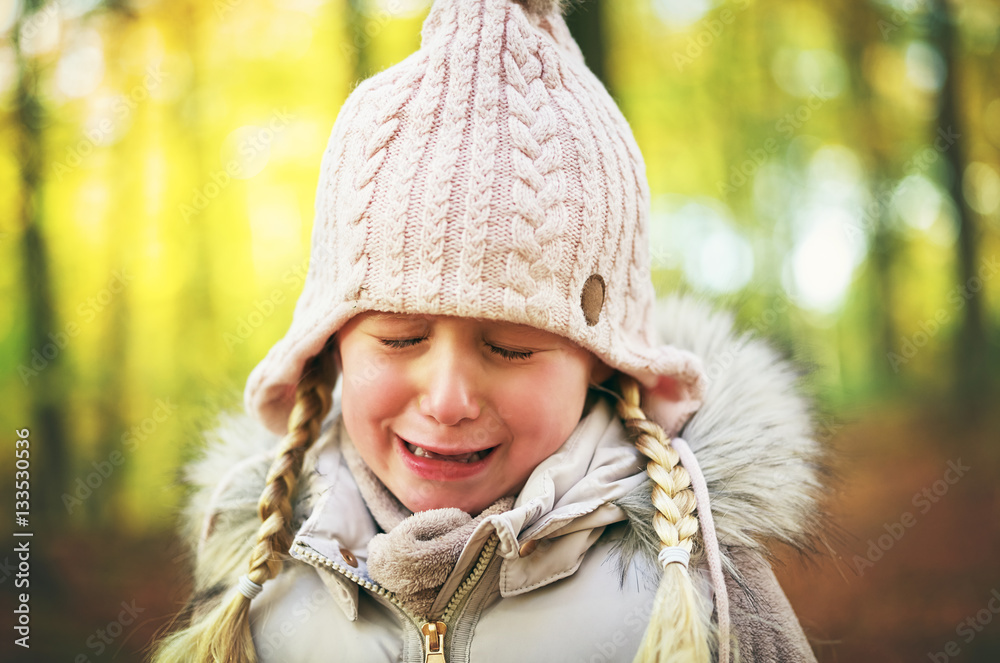 A crying little girl in autumn forrest