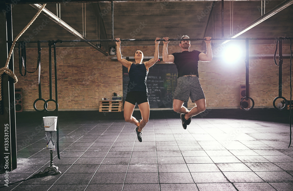 Front shot of two sportsmen doing pull-ups