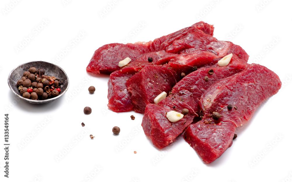 Pieces of meat with garlic isolated on white background. Raw beef. Top view.