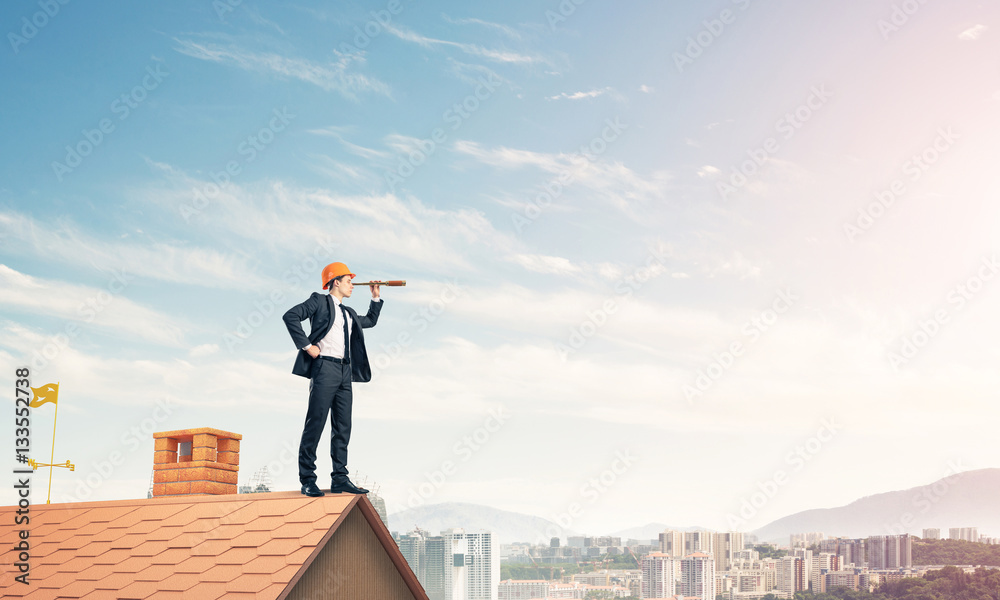 Engineer man standing on roof and looking in spyglass. Mixed med