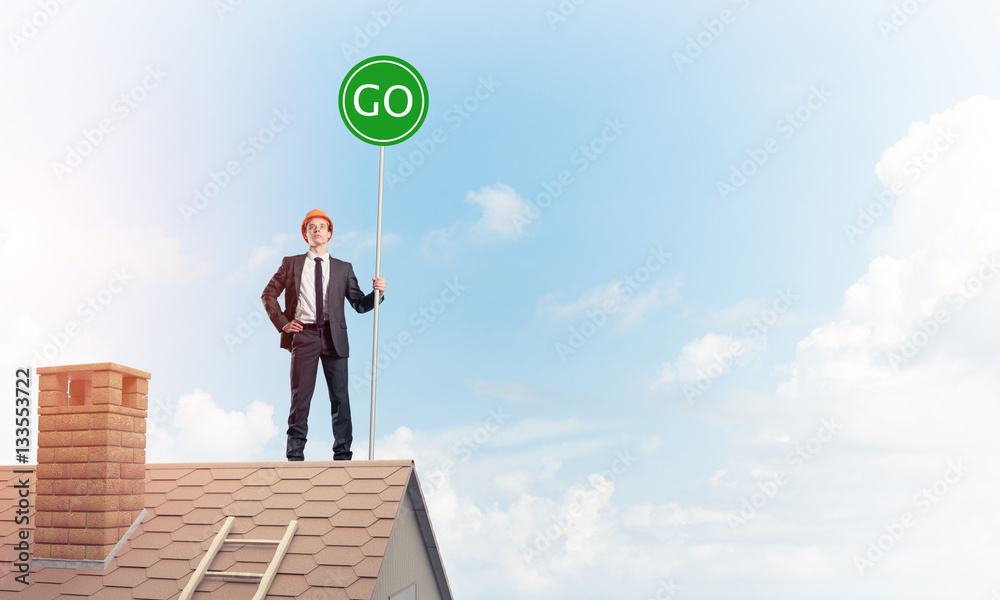 Businessman in suit on house top with ecology concept signboard.