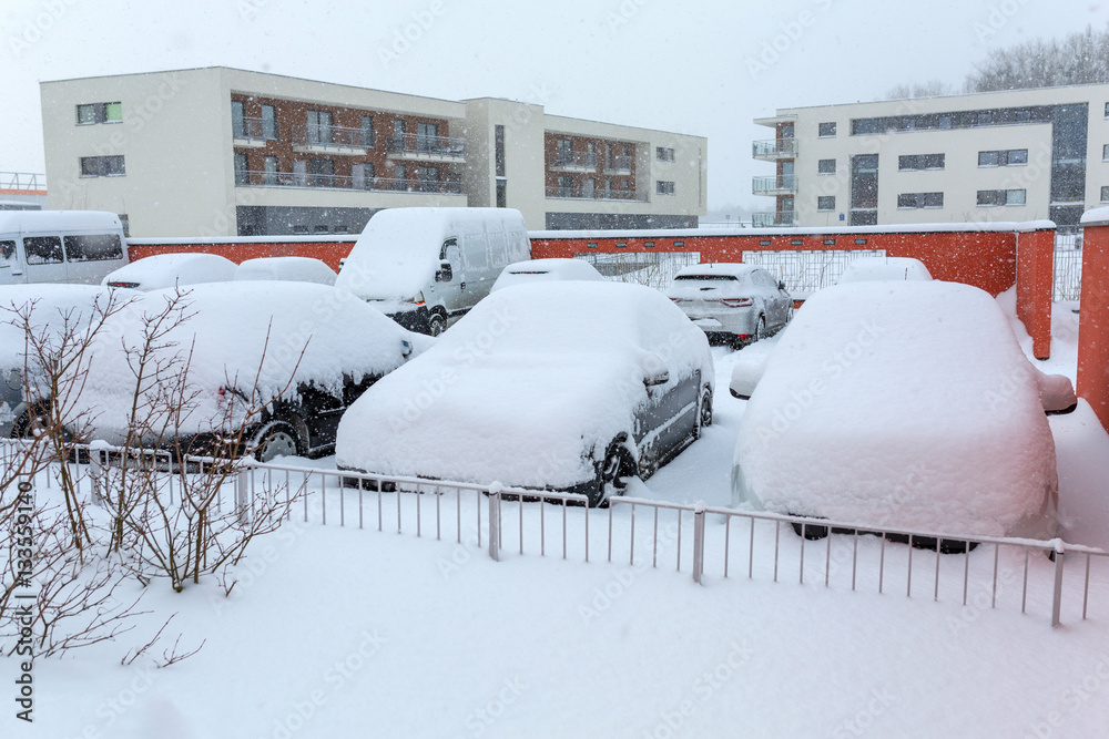 Snowy street with cars after winter snowfall in Poland