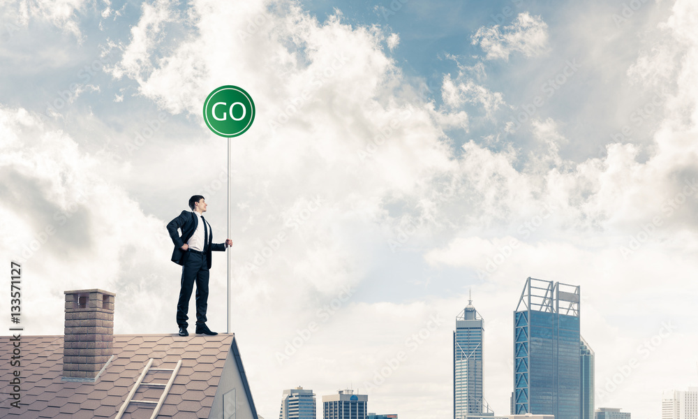 Businessman in suit on house top with ecology concept signboard.