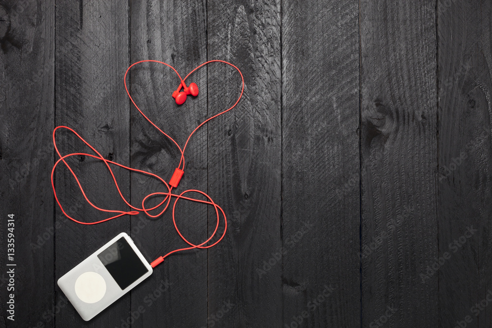 music player with red earphone on black wood background.