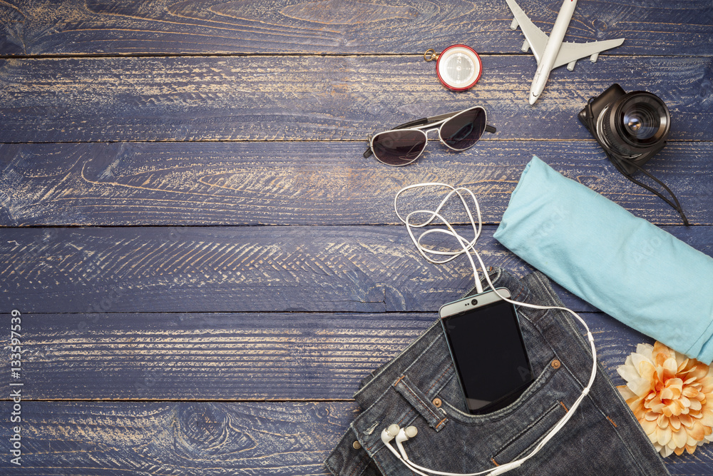 Outfits and accessories of traveler on blue wooden background.