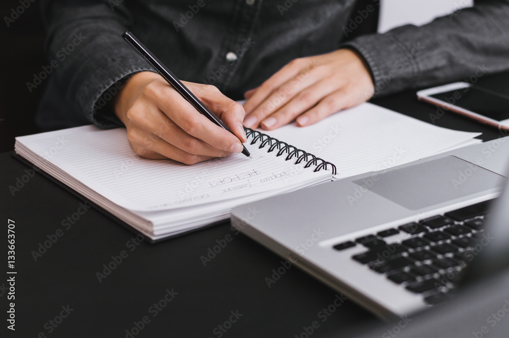 Woman freelancer female hands with pen writing on notebook