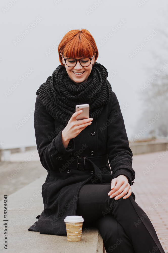 Happy woman calling on the mobile phone in the street in winter