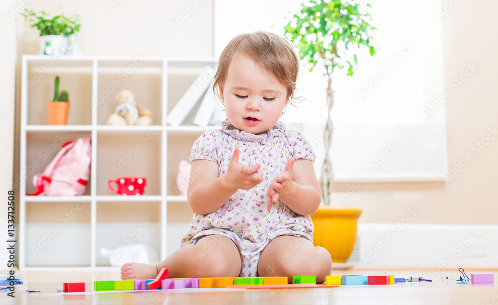 Happy toddler girl playing with her toys