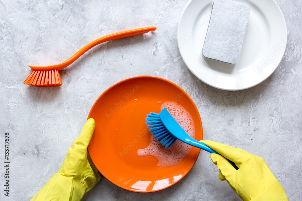 concept of woman washing dishes on gray background top view