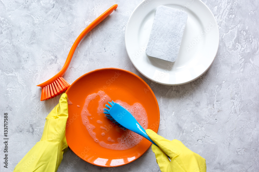 concept of woman washing dishes on gray background top view