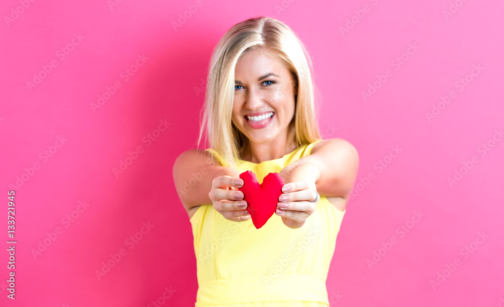 Happy young woman holding a heart cushion