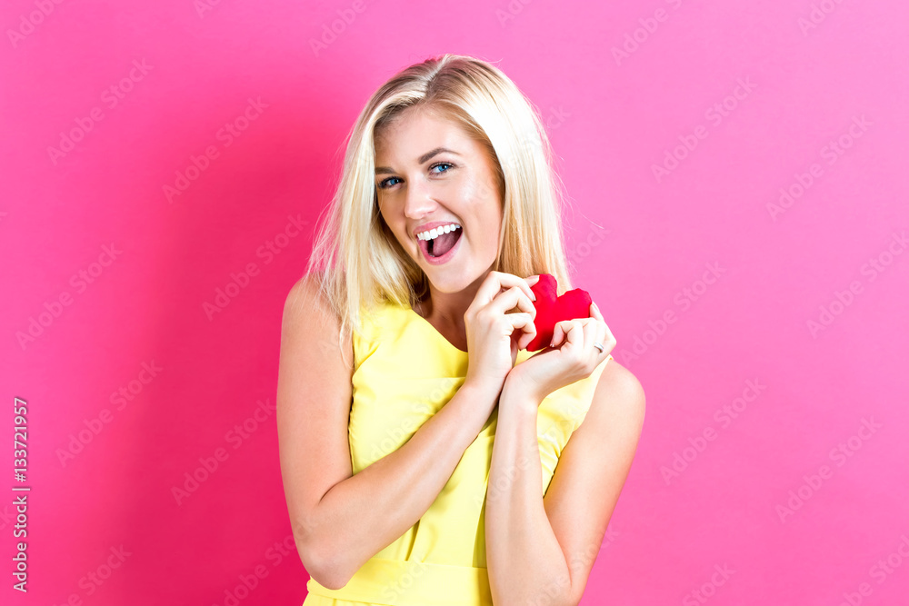 Happy young woman holding a heart cushion