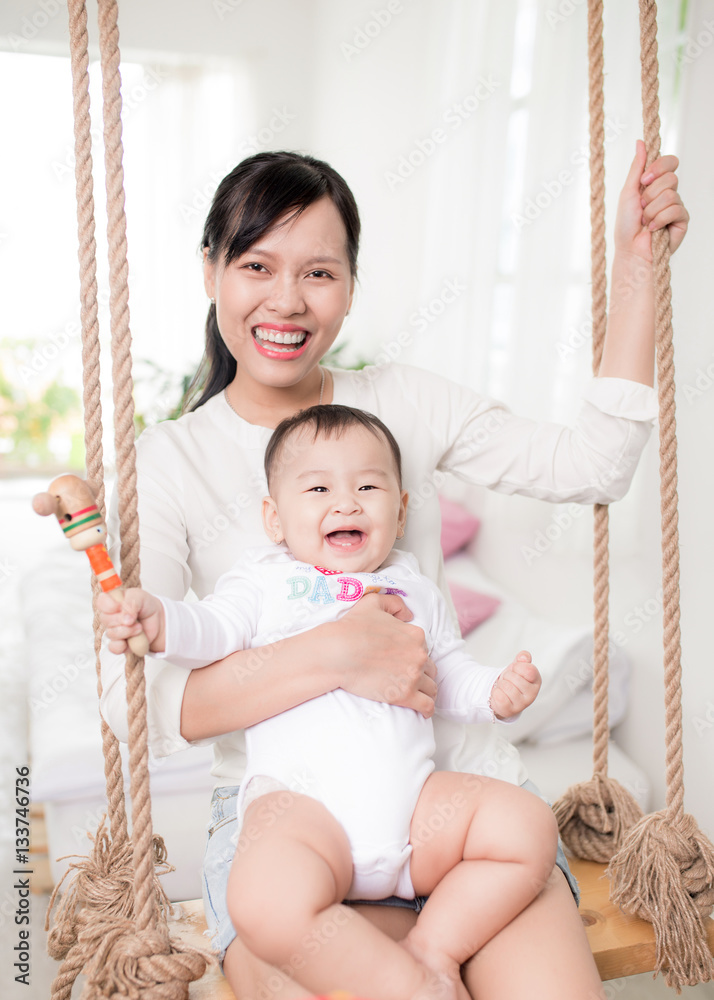 Portrait of happy asian mother and baby having fun together at h