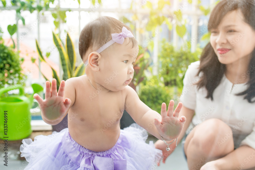 Little asian baby girl at home in white room stands near window