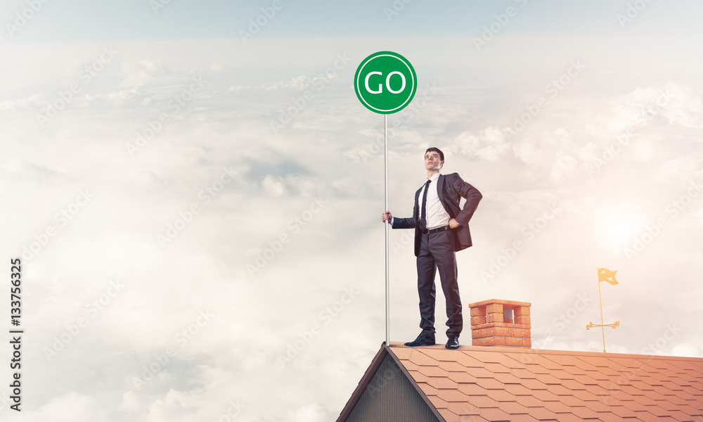 Businessman in suit on house top with ecology concept signboard.