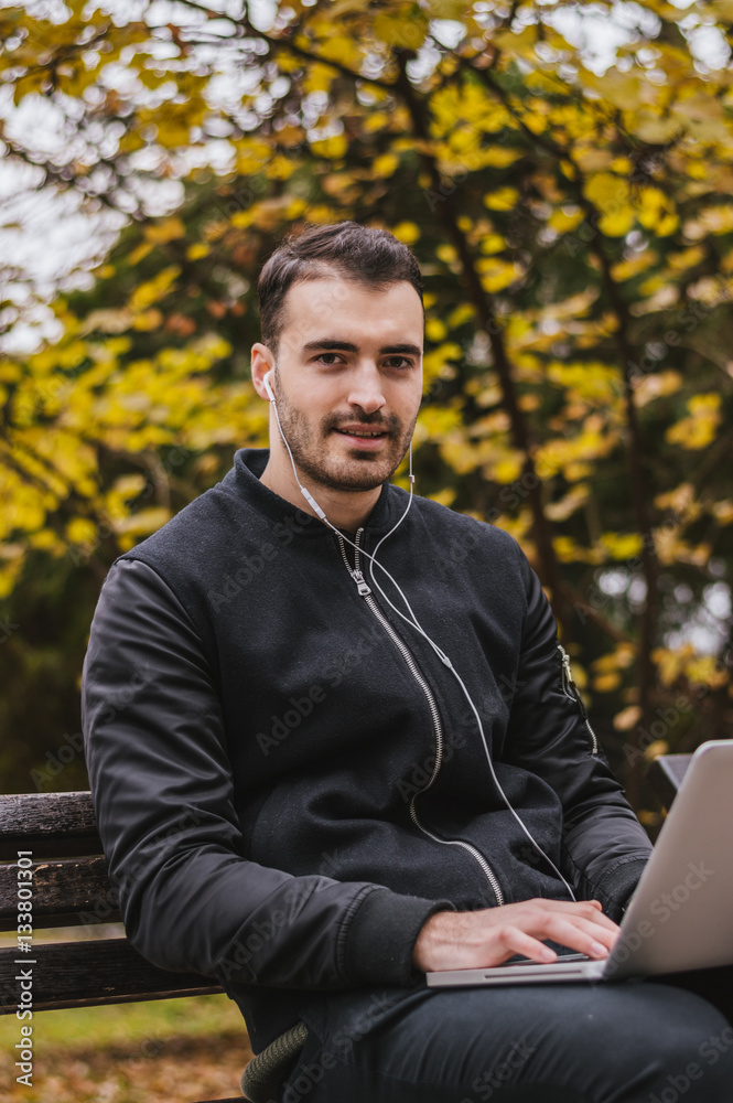 Handsome man working on his laptop outside