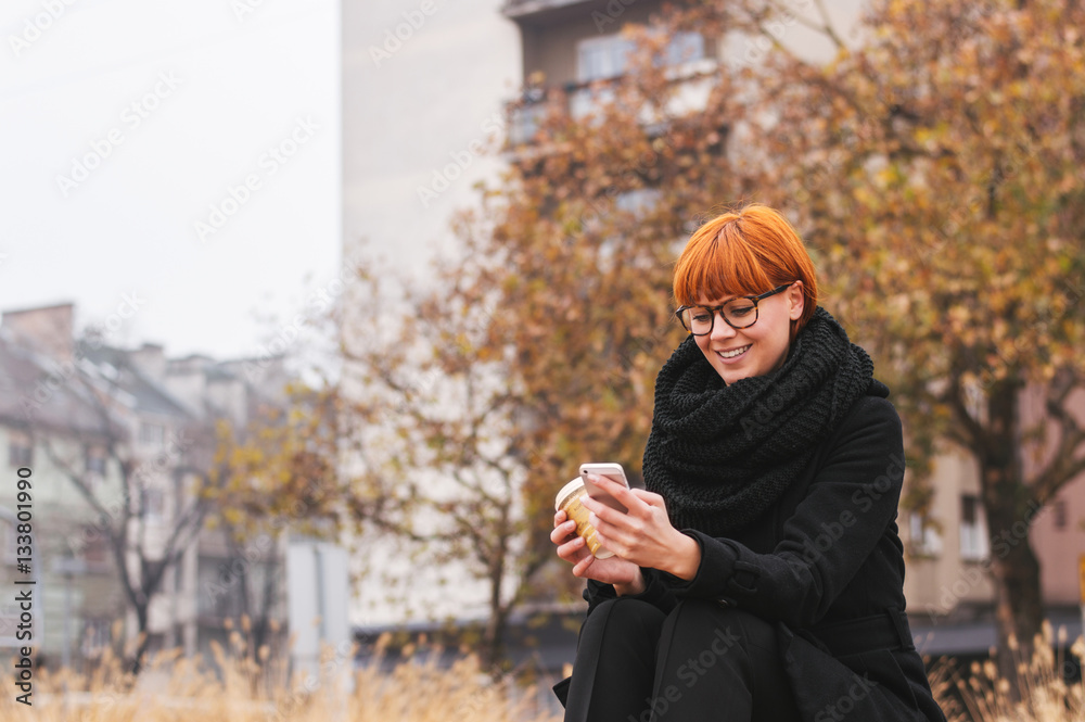 Girl waiting for a friend, looking at mobile