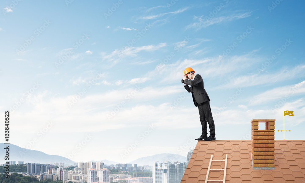 Engineer man standing on roof and looking in binoculars. Mixed media