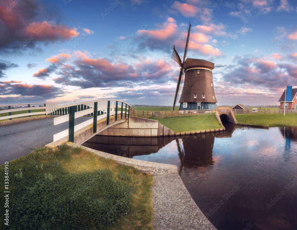 Windmill and bridge near the water canal at sunrise in Netherlands. Beautiful old dutch windmill aga