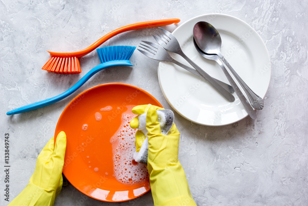 concept of woman washing dishes on gray background top view