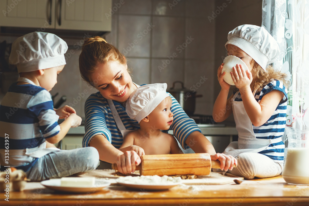 happy family in kitchen. mother and children preparing dough, ba