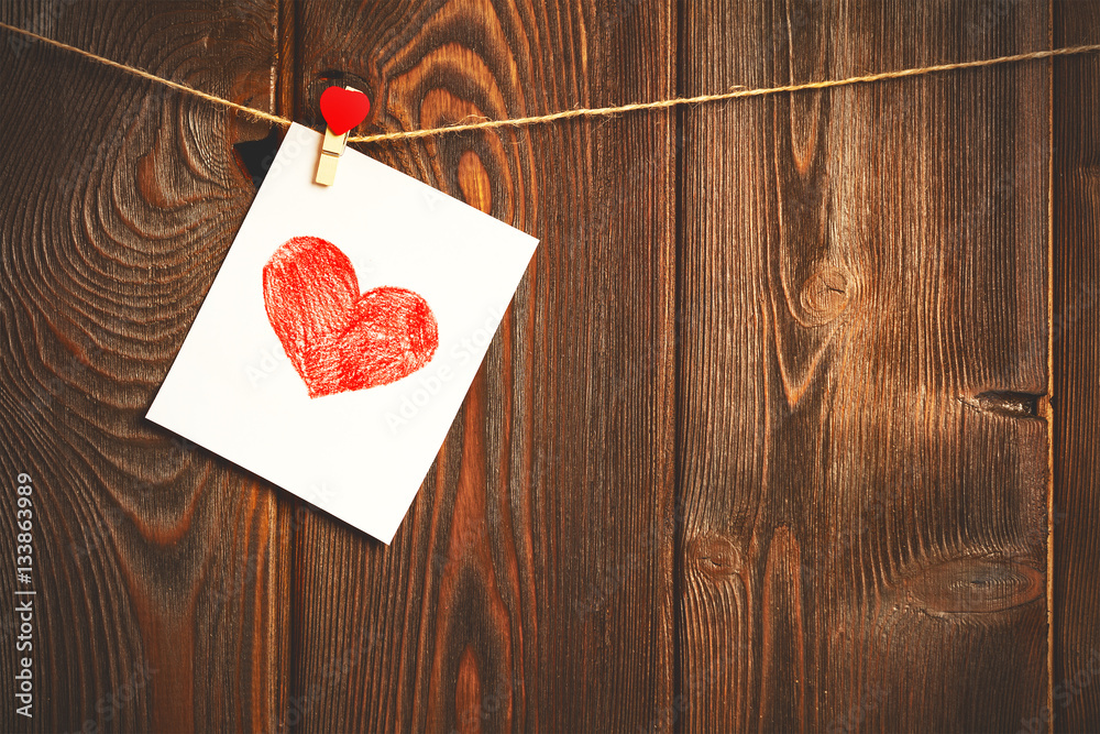 Card to day of St. Valentine and red heart on wooden