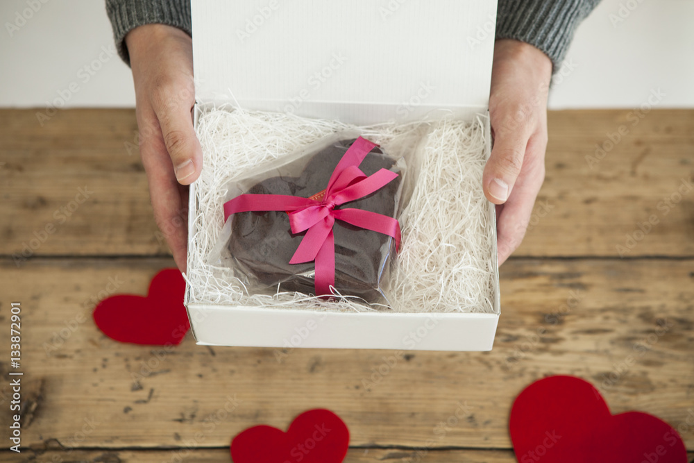 Male hands heart-shaped chocolate cake to lover