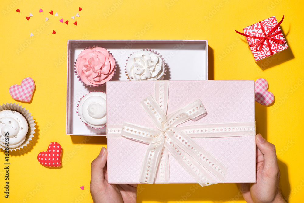 Delicious cupcake with paper box on yellow background