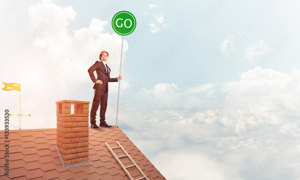 Businessman in suit on house top with ecology concept signboard.