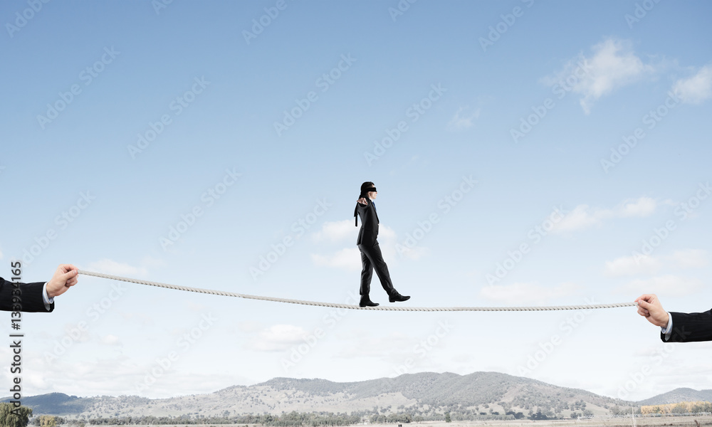 Business concept of risk support and assistance with man balancing on rope