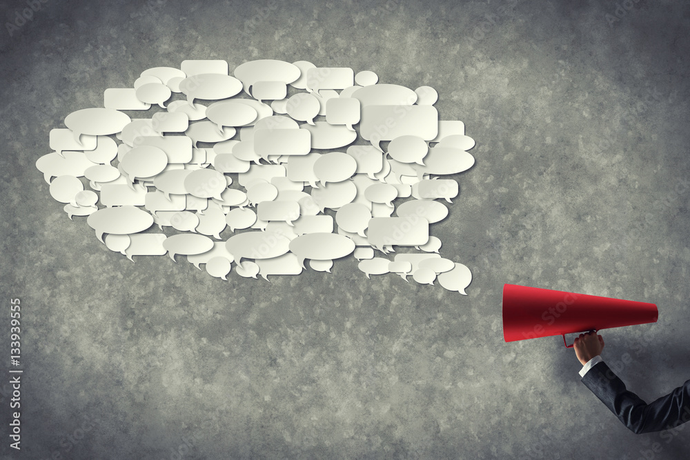 Hand of businesswoman holding red paper trumpet and speech cloud coming out