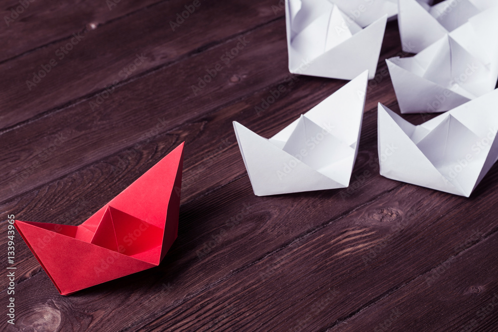 Business leadership concept with white and color paper boats on 