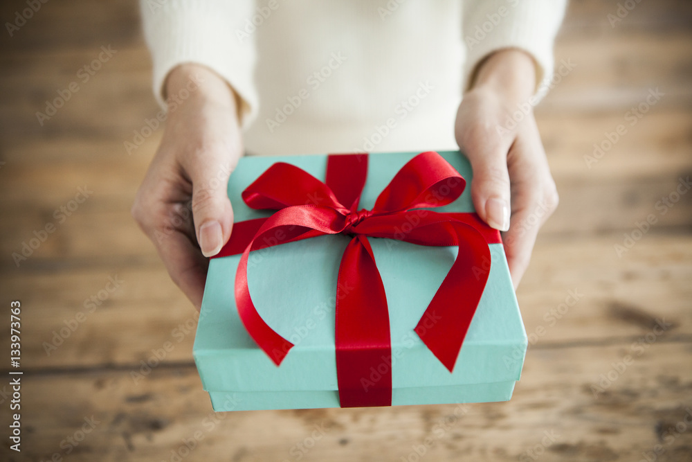 The woman is handing a gift box