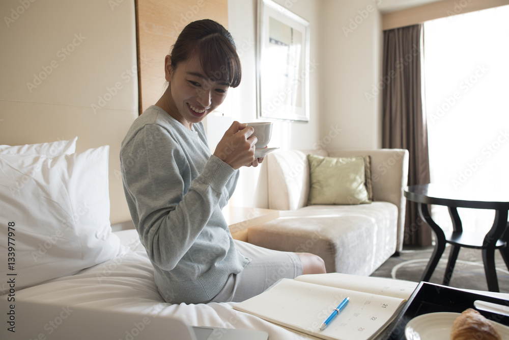 那个女人坐在酒店房间的床上喝咖啡