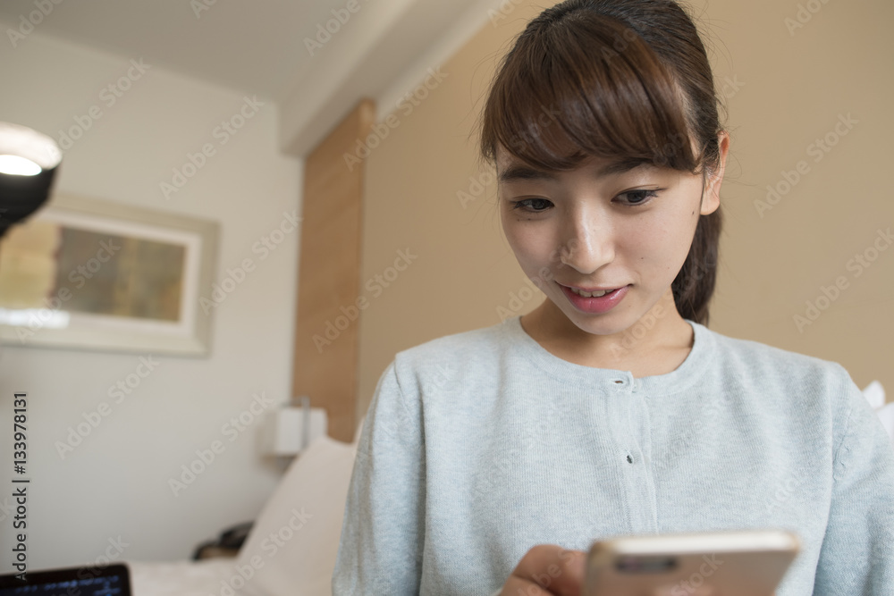 A woman is watching a smartphone in a hotel room