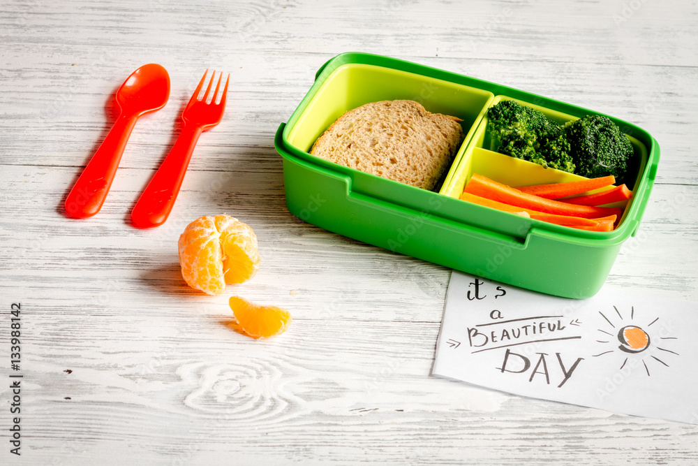 lunch box for kid with fresh vegetables on wooden background