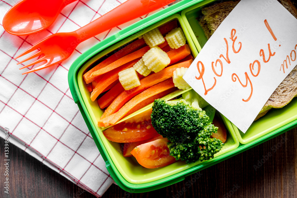 green lunch box for kid on wooden background top view