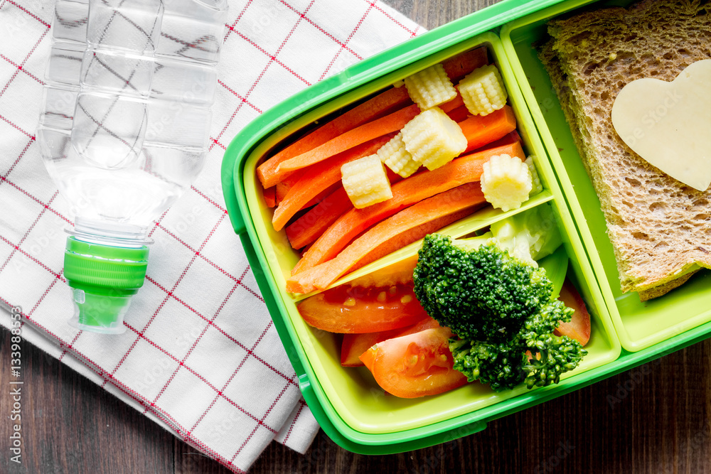 green lunch box for kid on wooden background top view