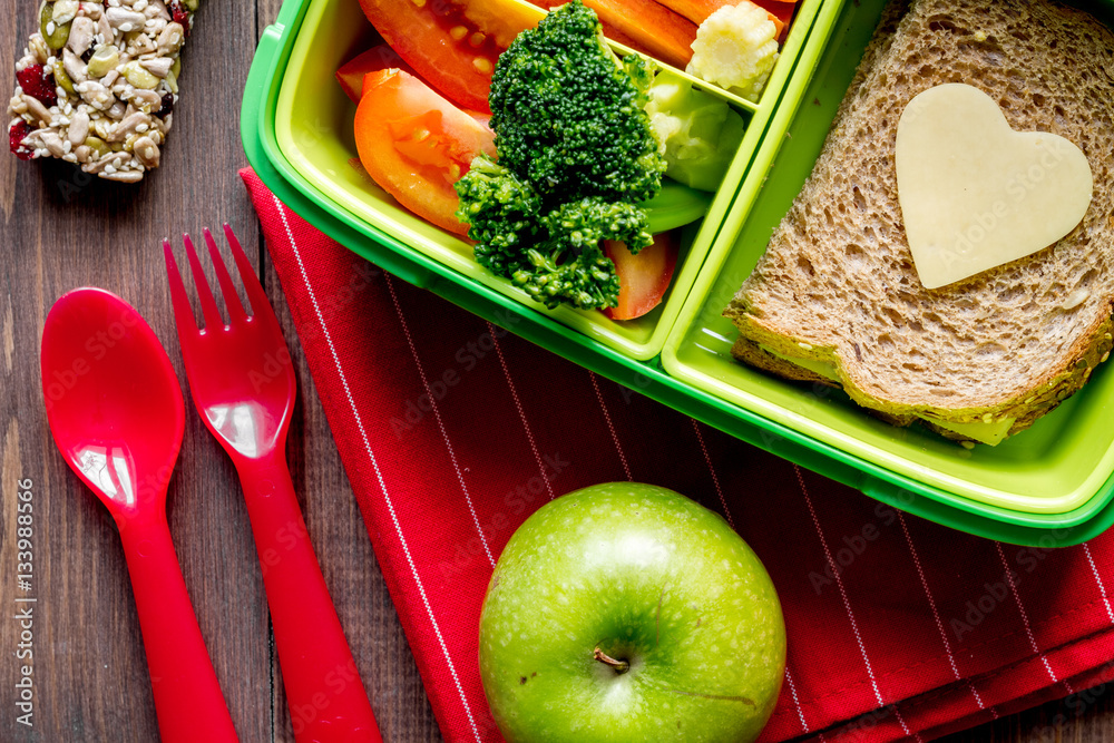 green lunch box for kid on wooden background top view