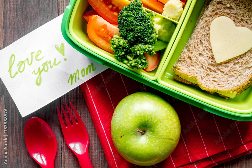 green lunch box for kid on wooden background top view