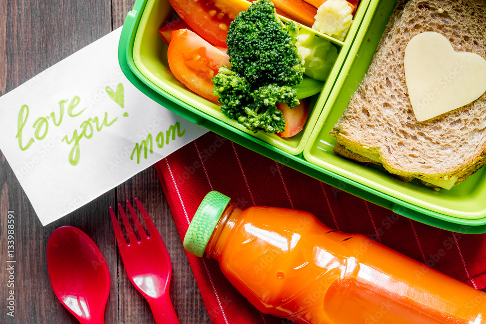 green lunch box for kid on wooden background top view