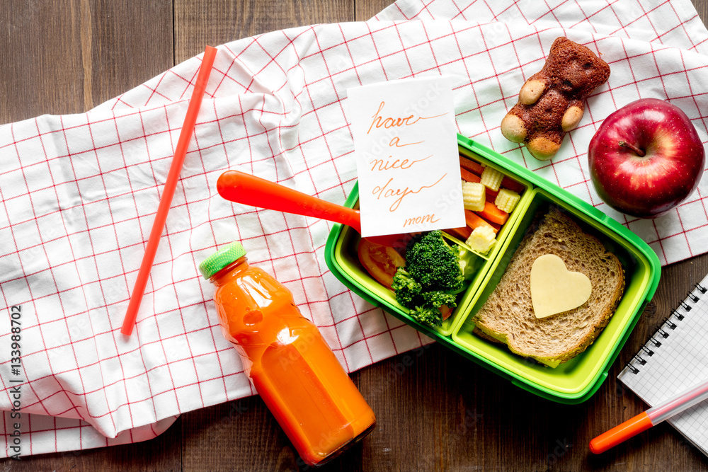 green lunch box for kid on wooden background top view