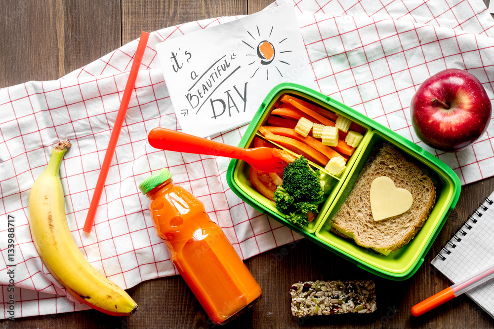 green lunch box for kid on wooden background top view