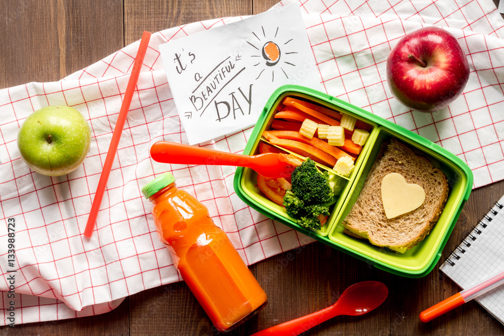 green lunch box for kid on wooden background top view