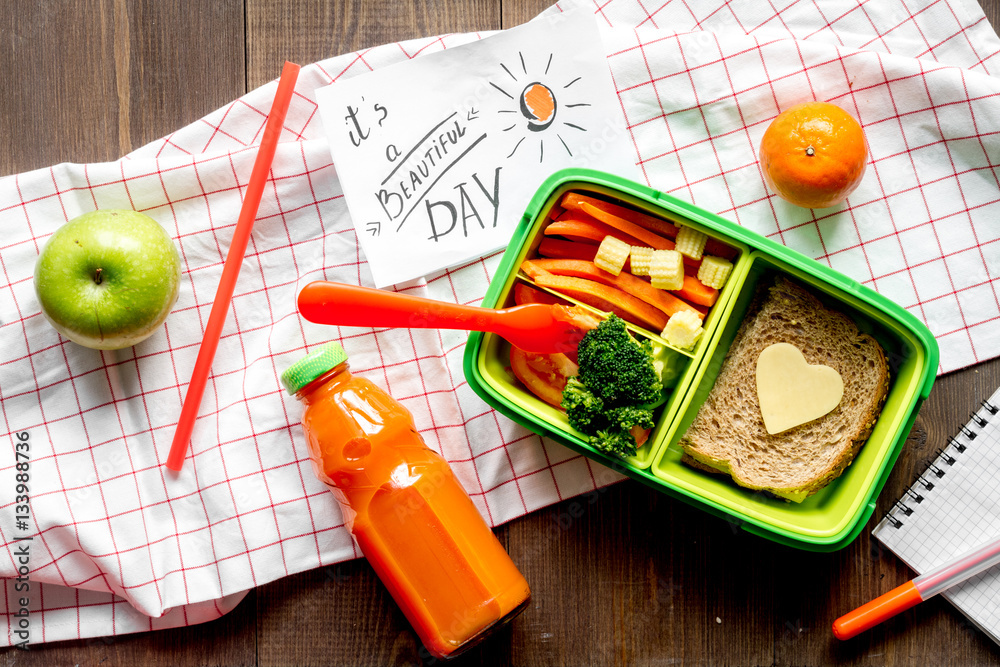 green lunch box for kid on wooden background top view