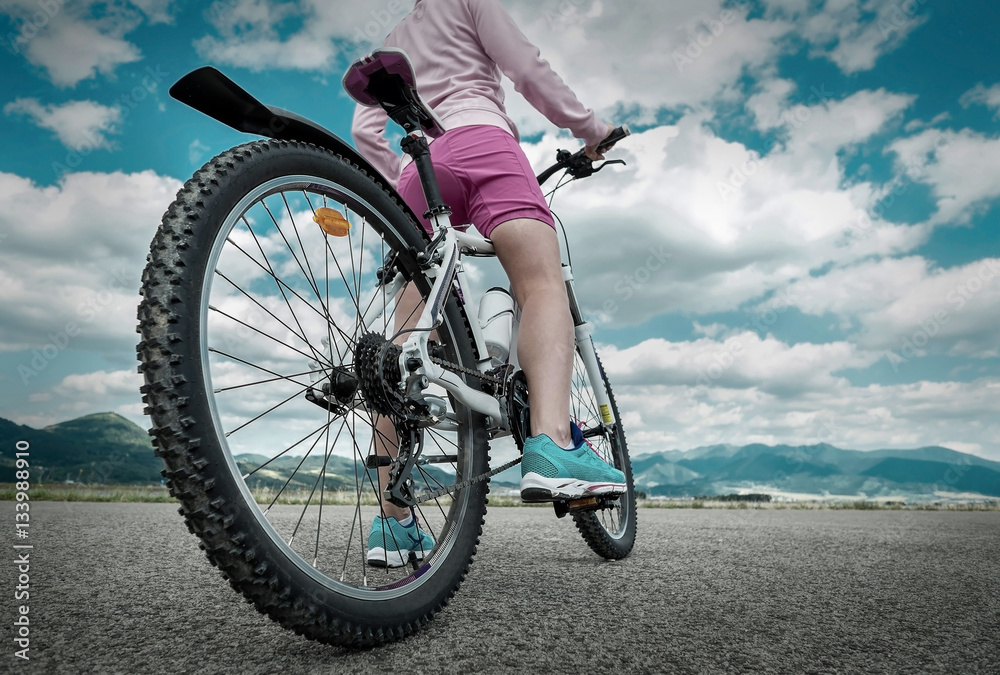 Beautiful woman in helmet and glasses stay on the bicycle under