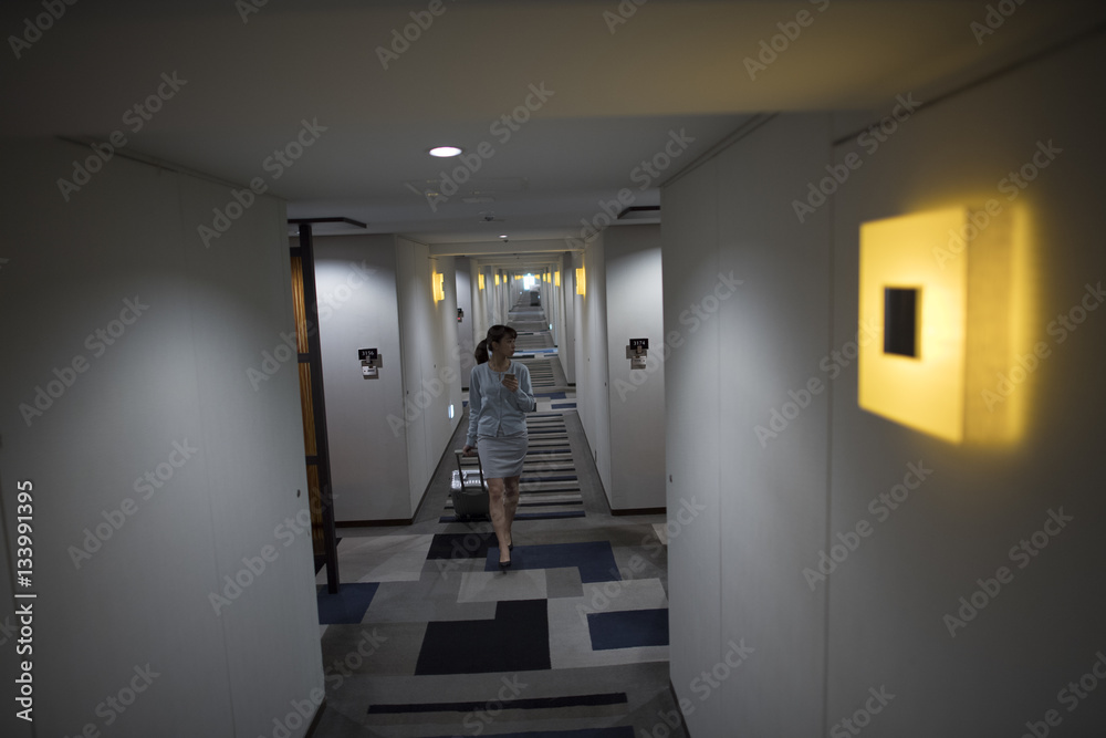 Women are walking through the hotel corridor with a suitcase