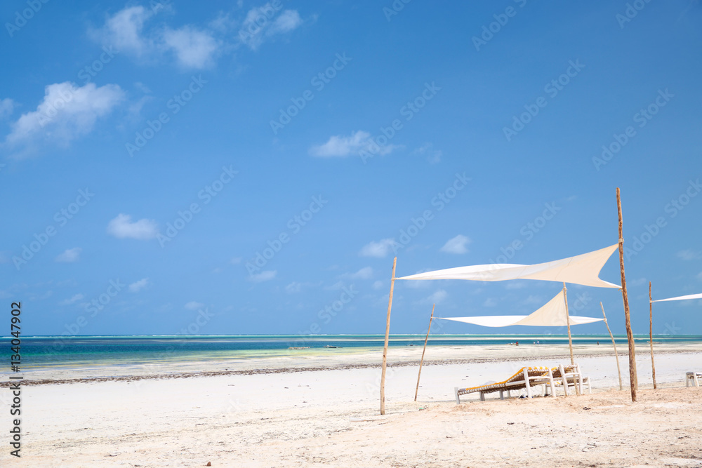 Beach with wooden deck chairs and tents in Zanzibar, Tanzania